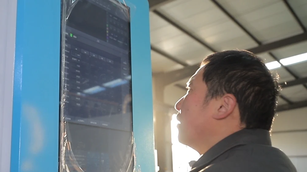 Un ingénieur d'usine analyse les données de production du ROI sur un écran tactile situé à côté d'une machine de découpe laser à fibre optique haute puissance utilisée pour l'usinage de tôles.