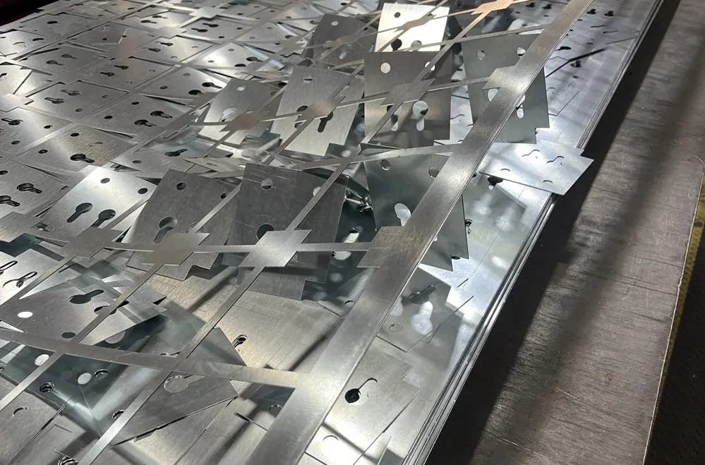 Batch of air assist laser cut sheet metal parts stacked on a laser cutting workstation