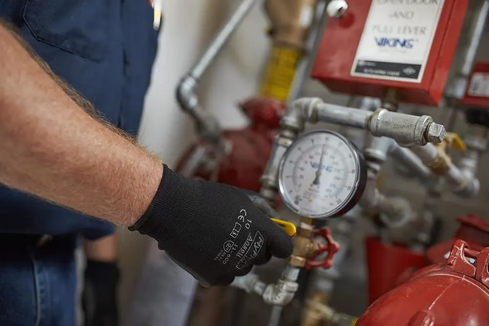 Technician checking the pressure gauge and filter status on a compressor system