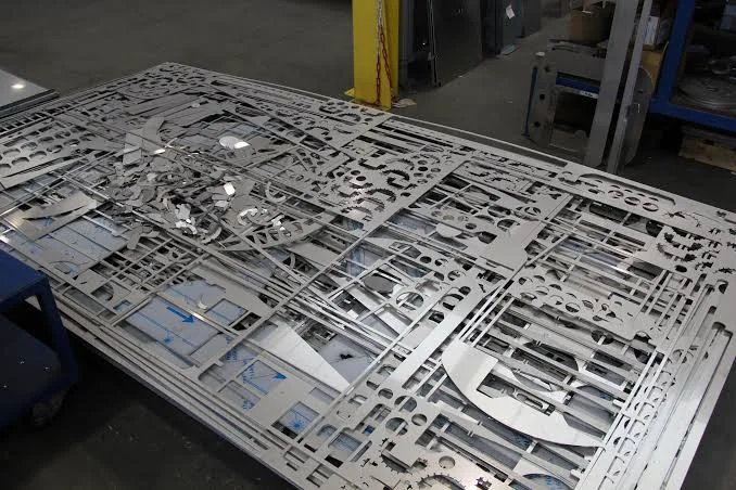 Metal sheet scrap skeleton after laser cutting parts sorting showing material utilization in fabrication workshop