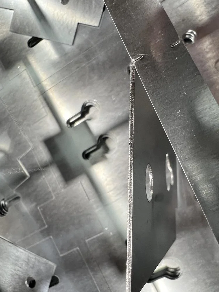 Overhead view of laser-cut parts stacked beside skeleton with visible micro-joint marks after automated unloading