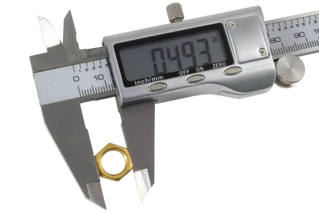 Machinist measuring precision of a laser cut sheet metal part with a digital caliper
