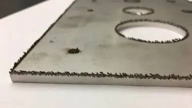 Fabrication worker grinding dross and deburring outsourced laser cut parts before welding
