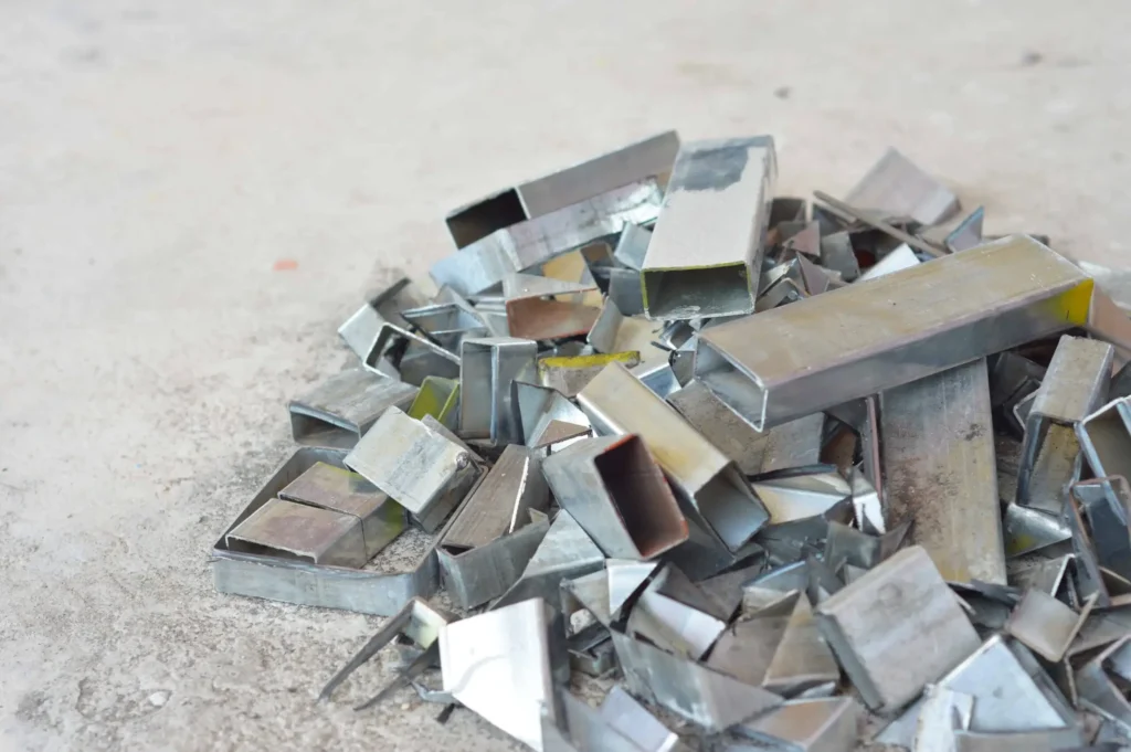 Steel tube remnants in a scrap bin showing long traditional tailings versus short zero-tailing drops