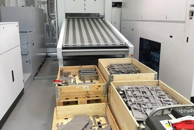 High-capacity metal fabrication shop floor with fiber laser cutter and crates of finished parts