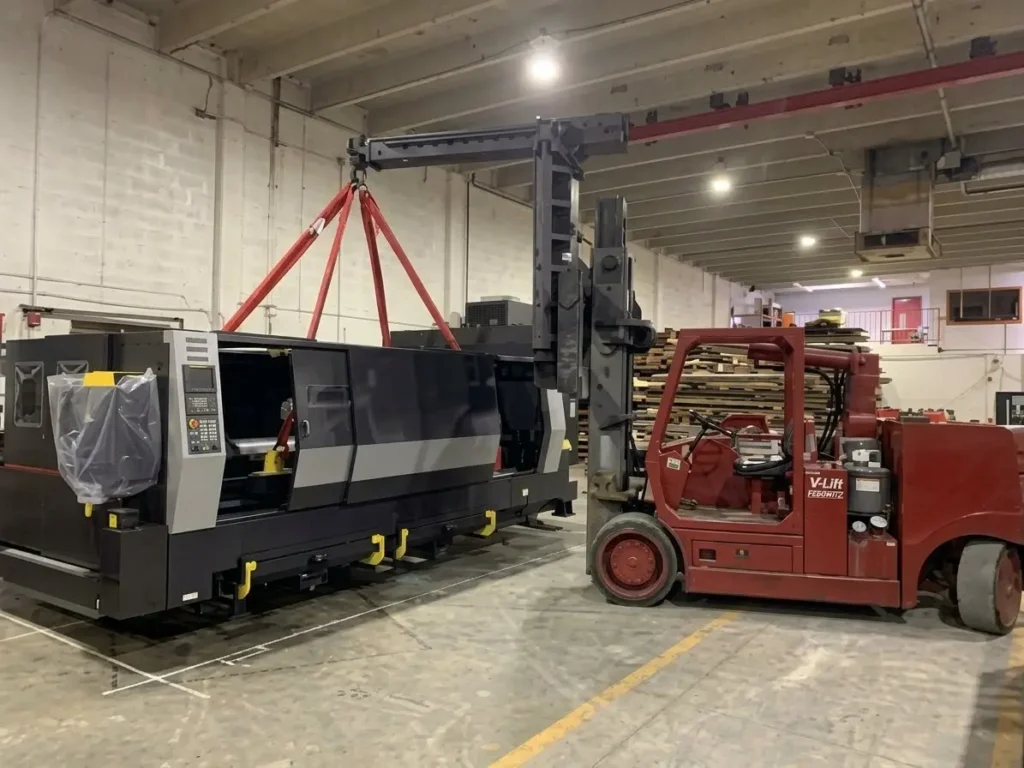 Heavy equipment rigging crane delivering fiber laser cutting machine to factory floor