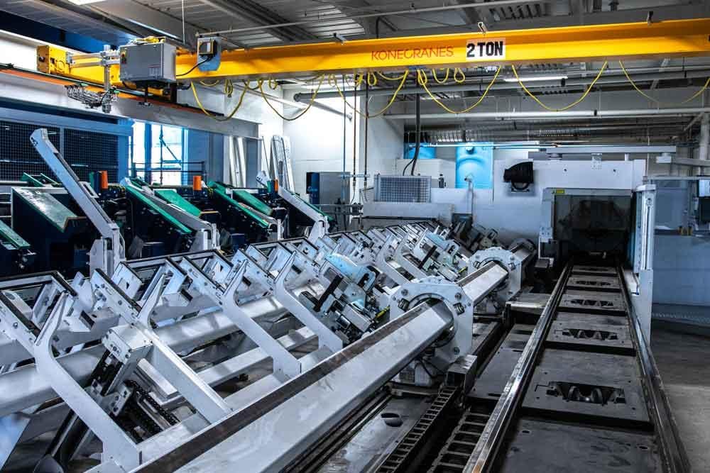 Industrial automatic bundle loader feeding structural tubes into a tube laser cutting machine in heavy fabrication workshop Automatic bundle loader for laser load and unload automation on tube cutter